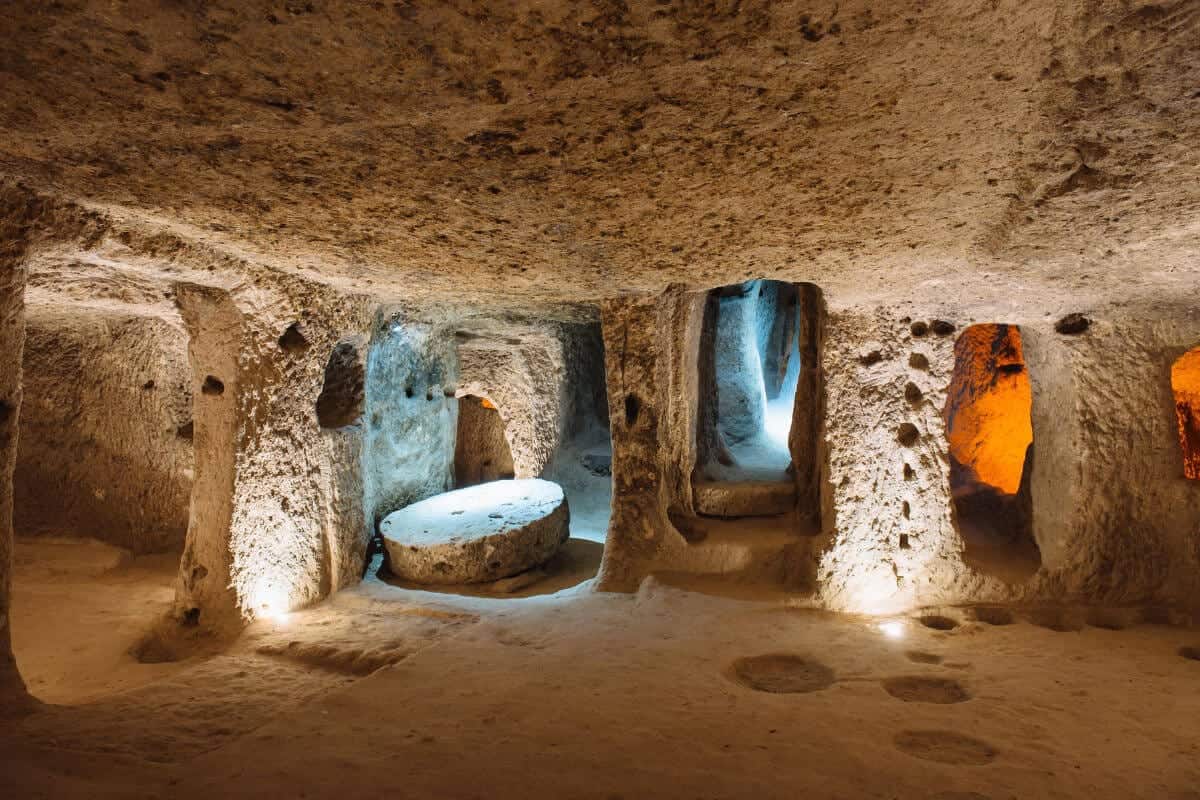 Illuminated stone corridors and chambers inside the ancient Derinkuyu underground city in Cappadocia, Turkey.