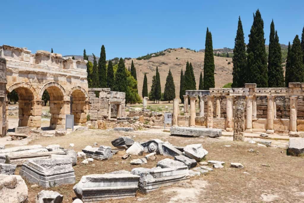 Stone ruins and Roman arches of Hierapolis ancient city under blue sky in Pamukkale, Turkey.