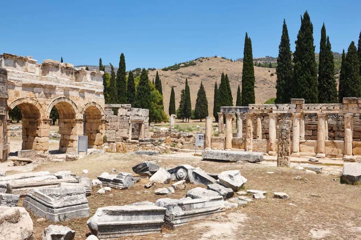 Stone ruins and Roman arches of Hierapolis ancient city under blue sky in Pamukkale, Turkey.
