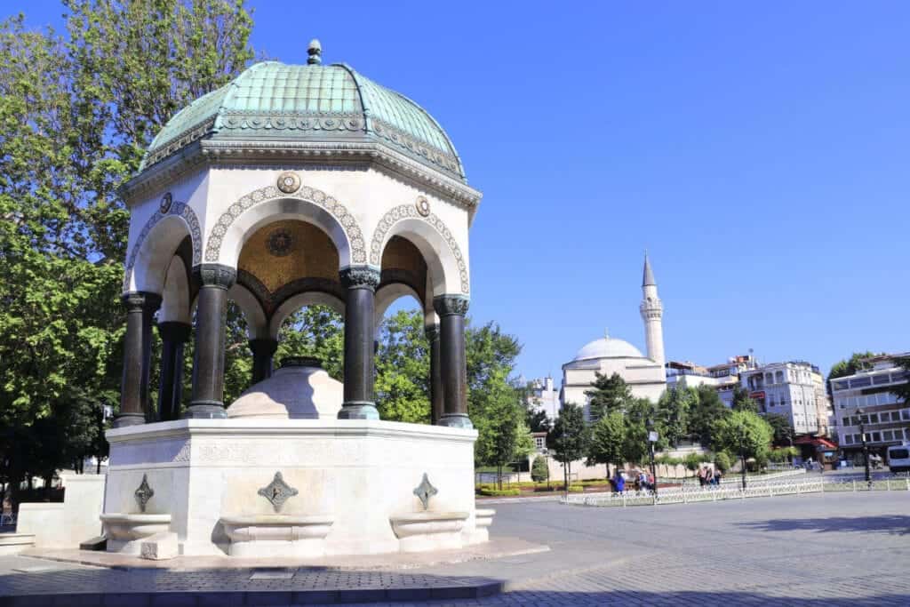 Ornate German Fountain with green dome and marble base in Sultanahmet Square, Istanbul, on a sunny day.
