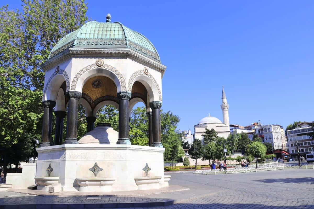 Ornate German Fountain with green dome and marble base in Sultanahmet Square, Istanbul, on a sunny day.