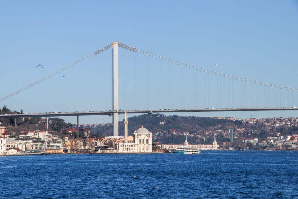 Ortaköy Mosque by the Bosphorus with the Bosphorus Bridge in the background under a vibrant Istanbul sky.