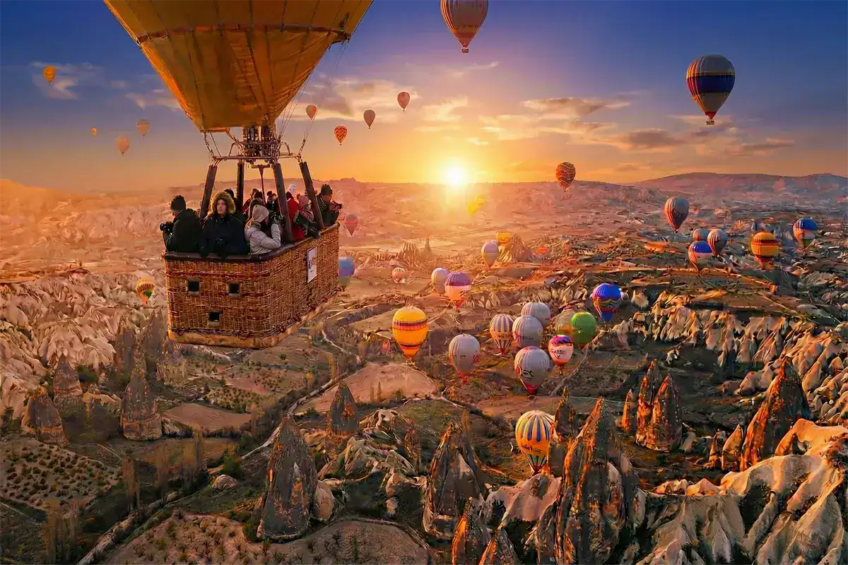 Tourists in a basket enjoying a sunrise hot air balloon flight over the fairy chimneys and unique rock formations of Cappadocia, the highlight experience of Cappadocia tours from Istanbul.