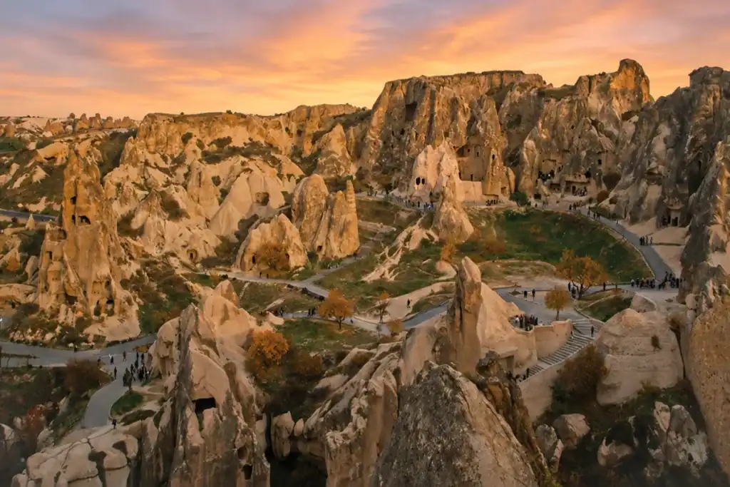 Sunrise view of Göreme Open-Air Museum in Cappadocia with ancient cave churches, fairy chimneys, and winding walking paths.