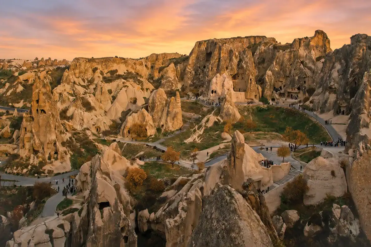 Sunrise view of Göreme Open-Air Museum in Cappadocia with ancient cave churches, fairy chimneys, and winding walking paths.